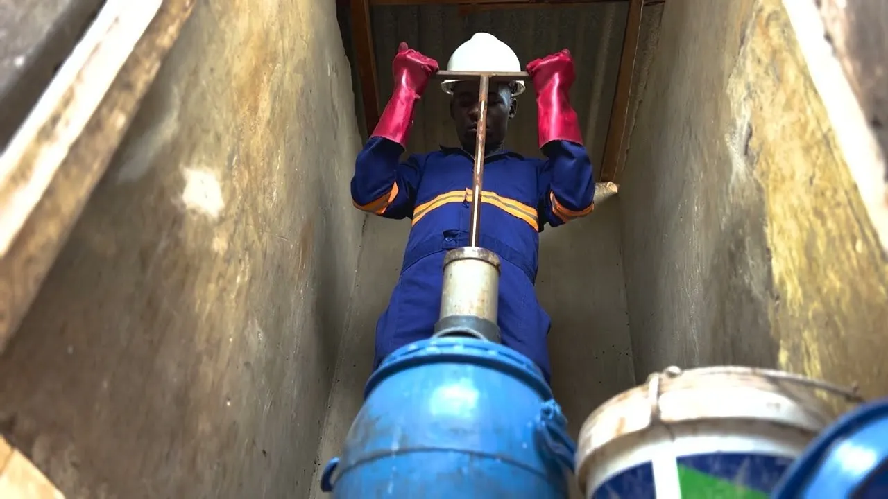 Operator using a Gulper to empty sludge into a collection drum